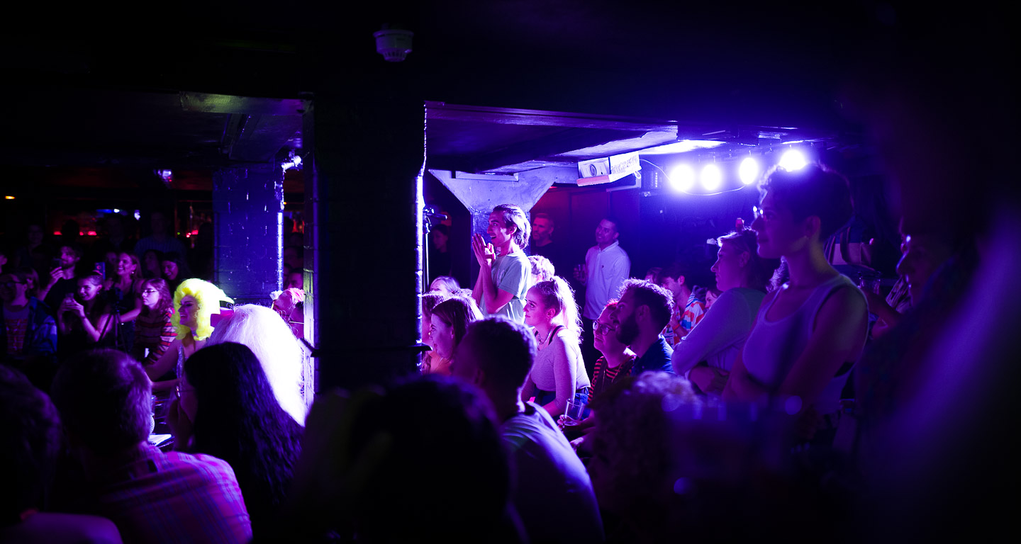 Crowd reacting in awe and amusement to a drag performance